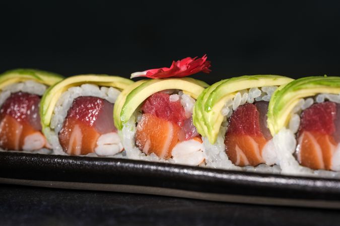 Delicious sushi rolls with avocado slices served on tray