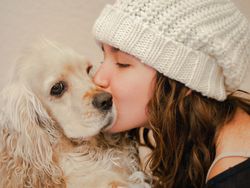 Teen in hat kissing dog