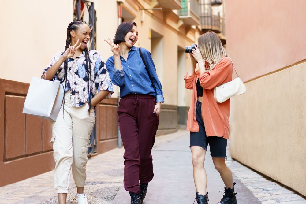Three women strolling down narrow lane taking photos