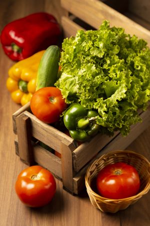 Crate of fresh vegetables on wooden table, vertical