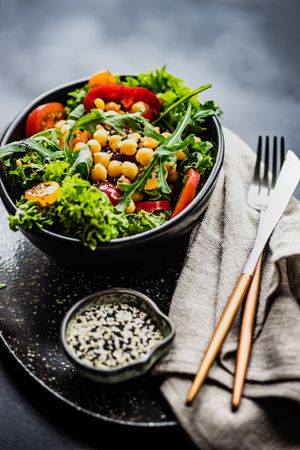 Organic vegetable salad with garbanzo beans and side of sesame seeds