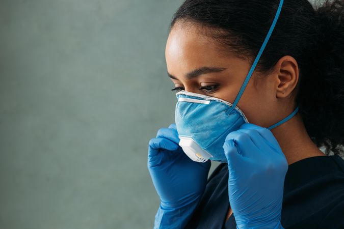 Side view of Black female doctor adjusting her protective mask