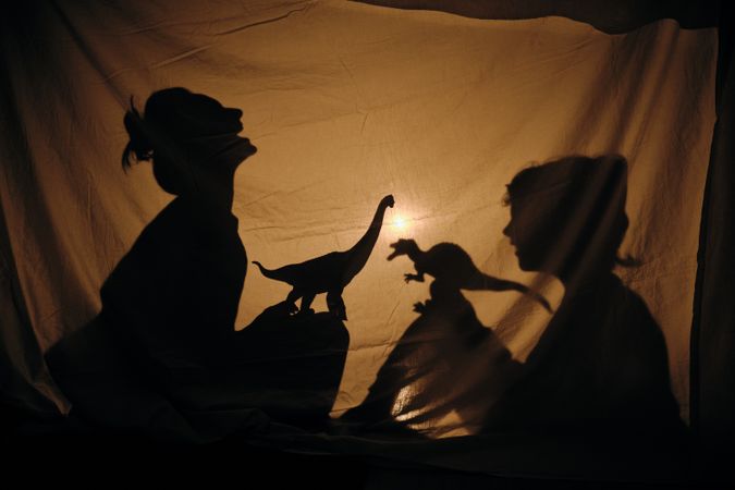 Mom and son playing with dinosaurs in shadow theater