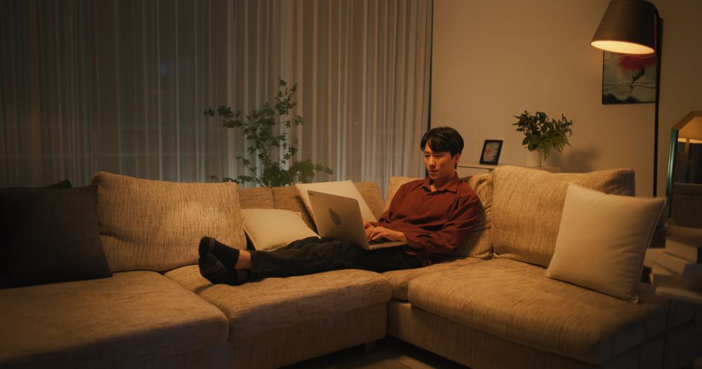 Asian Male Browsing Internet in The Evening in His Apartment