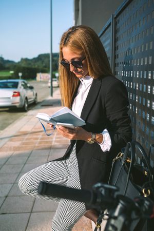 Businesswoman reading diary with her scooter next