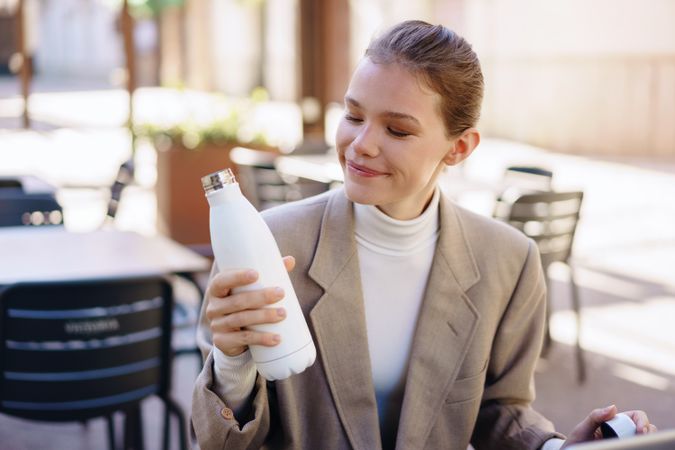 A Woman Happily Enjoying Her Colorful Water Bottle While Seated in a Cafeteria Setting