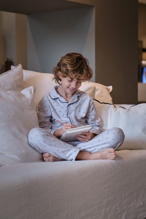 Cheerful boy in pajama doing homework