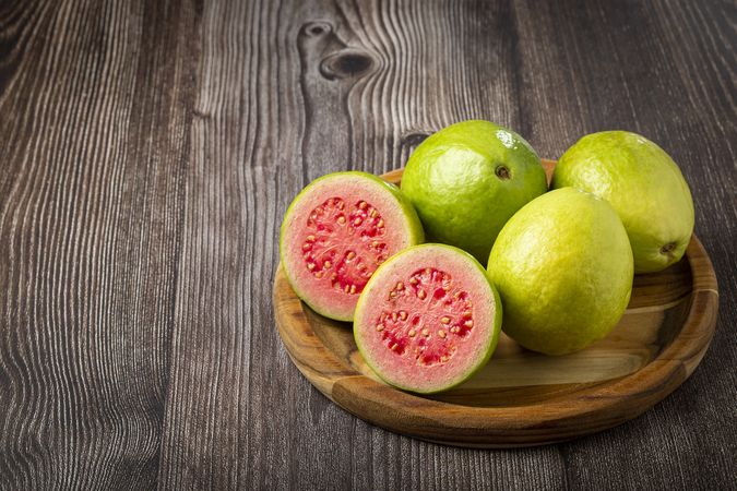 Fresh sliced guavas on wooden table.