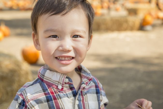 Smiling Biracial Young Boy Having Fun at the Pumpkin Patch