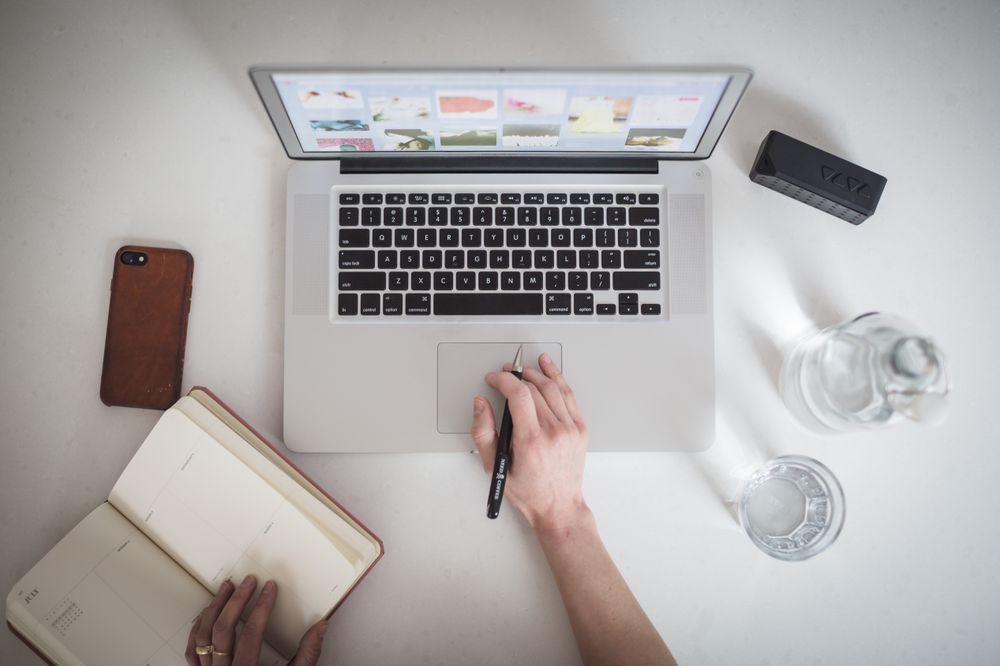 A person is working on a macbook laptop and on a table