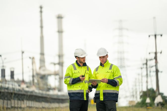 Engineer worker watching work monitor on digital tablet and talking to colleague