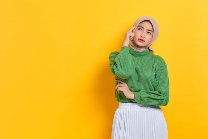 Woman in headscarf deep in thought with hand to her temples with copy space