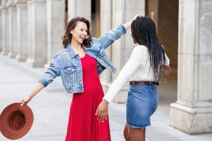 Female friends smiling and seeing each other for the first time in a while on an outdoor street