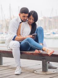 Man bonging smiling woman having fun with smartphone