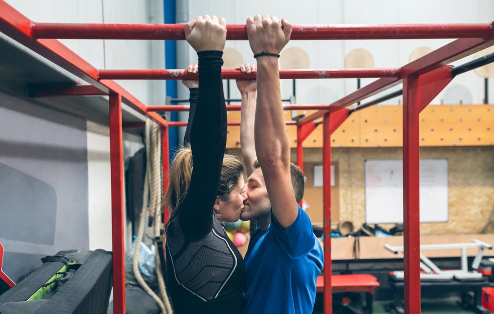 Athletes kissing exercising on monkey bars