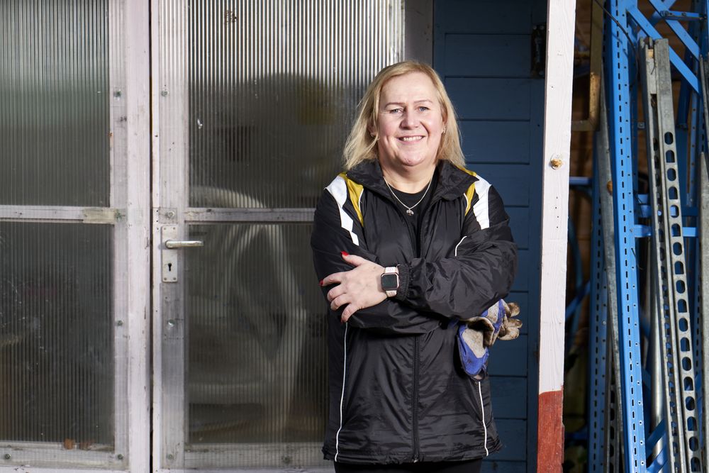 Woman standing in front of an outdoor shed with arms crossed outside