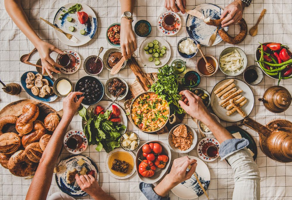 Group of people at Turkish style fresh breakfast with eggs, breads, vegetables, drinking tea