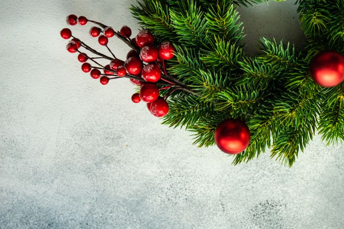 Christmas wreath with red baubles and holly on marble counter with copy space