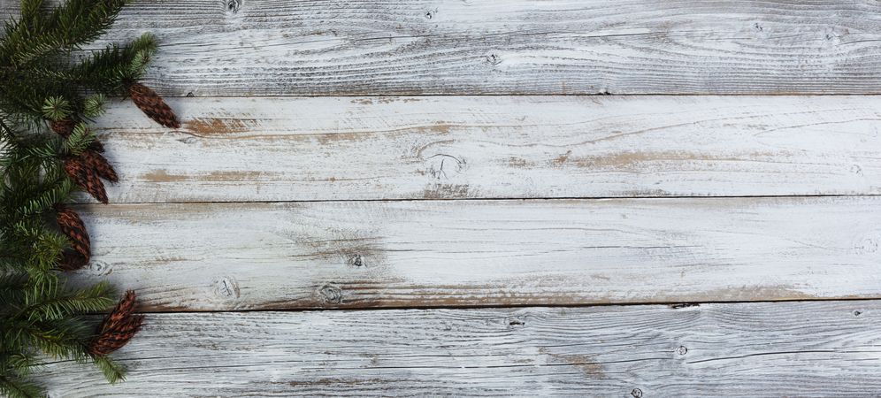 Christmas decoration with real fir branches forming left border on aged wood setting