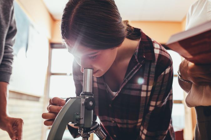 Student looking through microscope in biology class