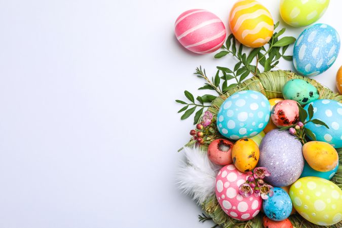 Flat lay composition with nest, Easter eggs, feathers and flowers on color background, space for text