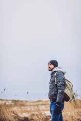 Man walking between sand field with dry grass
