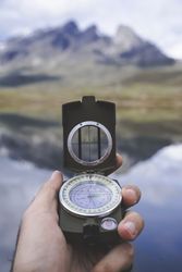Crop hand with compass near lake