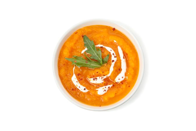 Top view of pumpkin soup with cream and herbs