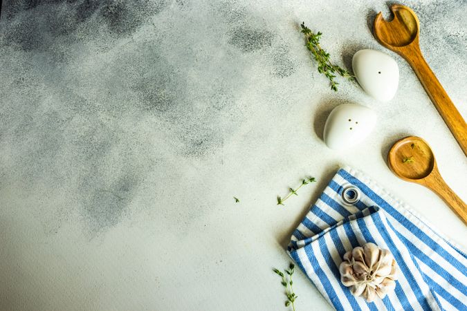 Top view of salt and pepper shakers, thyme and garlic on concrete background with copy space