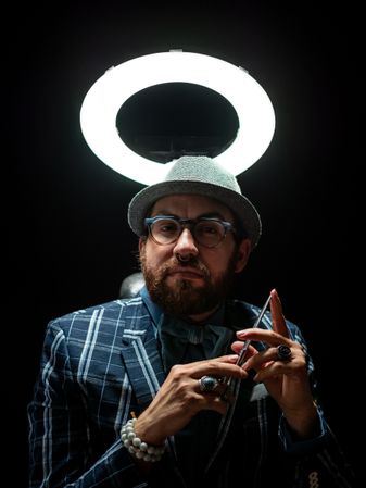 Well dressed man holding scissors and looking at camera