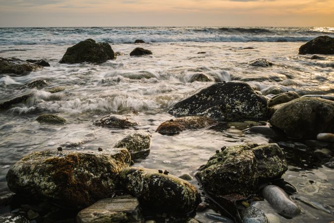 Stony seashore and waves at beautiful sunset