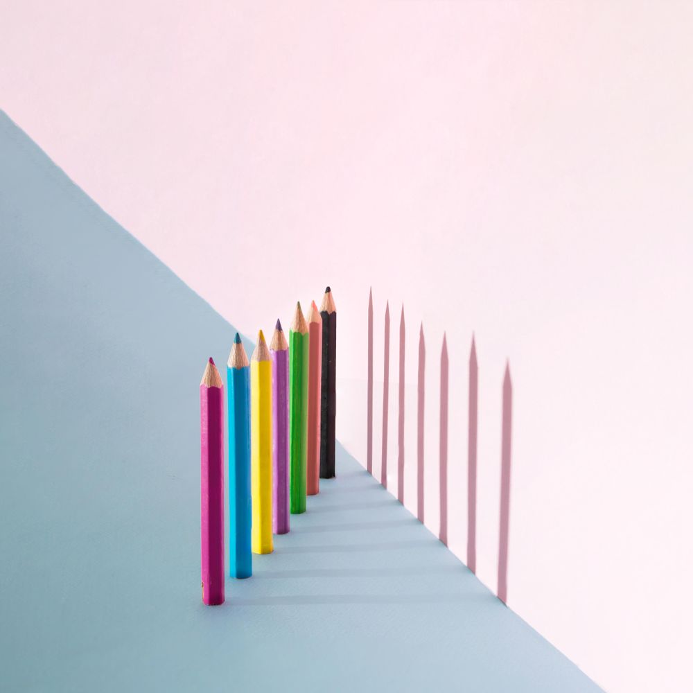 Row of color pencils on pastel background