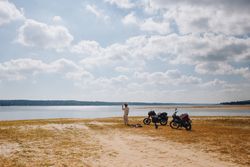Man taking photo next to two motorcycles