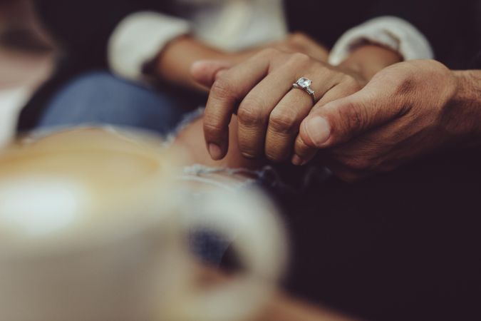 Man holding woman’s hand wearing engagement ring