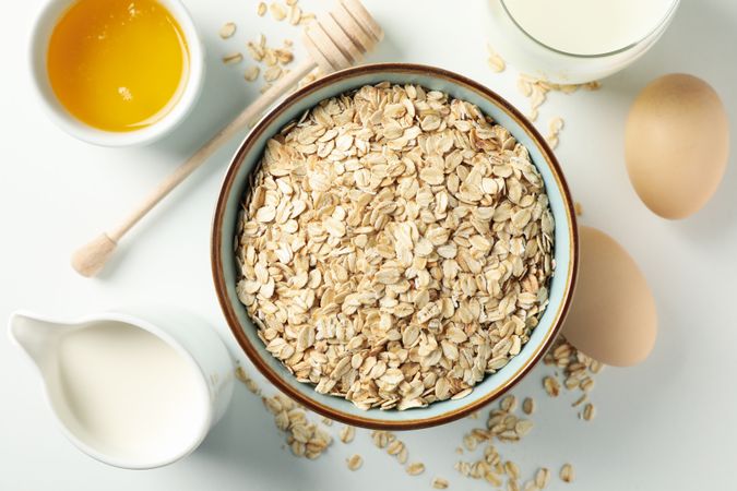Composition with oatmeal flakes on plain background, top view. Cooking breakfast