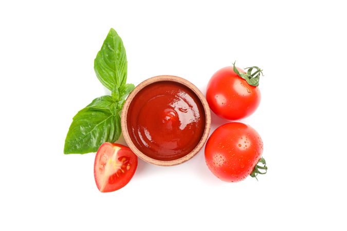 Fresh cherry tomatoes with basil and sauce isolated on blank background, top view. Ripe vegetables