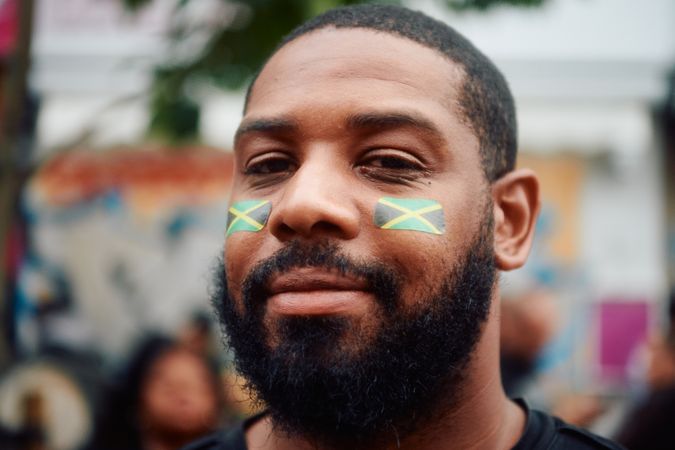 London, England, United Kingdom - August 28, 2022: Portrait of man with Jamaican flag on face