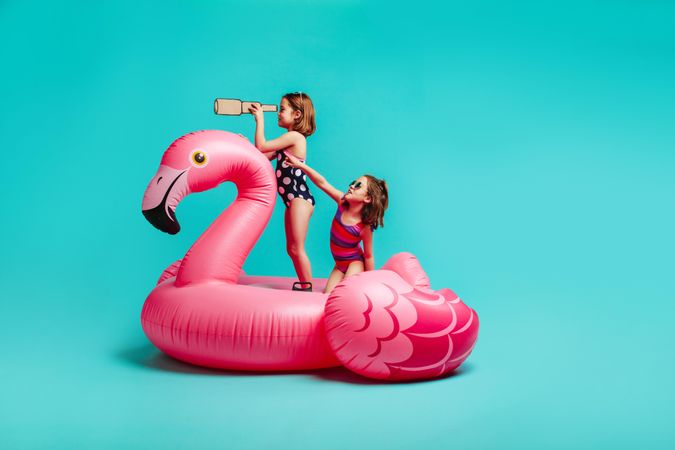 Two girls having fun on inflatable toy flamingo