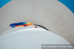 Person in a building waving rainbow flag bGX8e0
