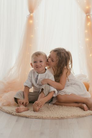 Sister kissing on cheek little brother at home