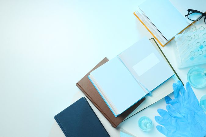 Books, notepads, flasks and gloves on light background, space for text