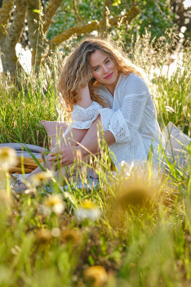 Smiling woman sitting on plaid in abundant park