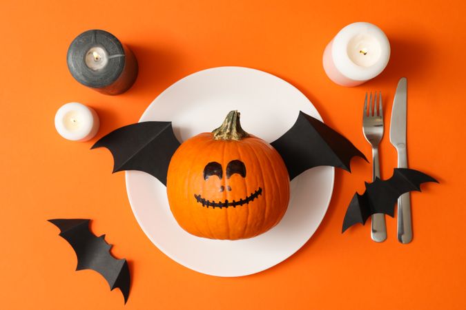 Table setting with halloween pumpkin on orange background