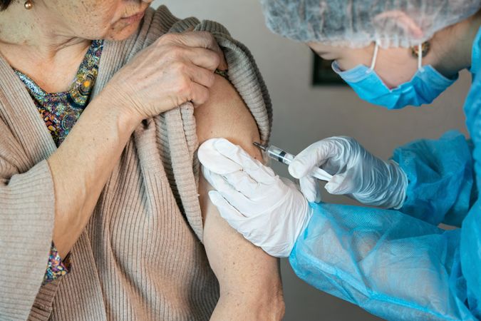 Older woman getting coronavirus vaccine by healthcare worker