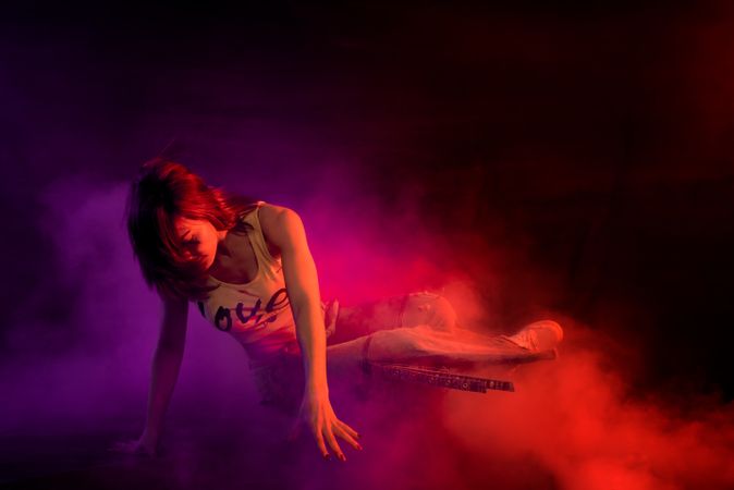 Young woman break dancing in colorful smoke
