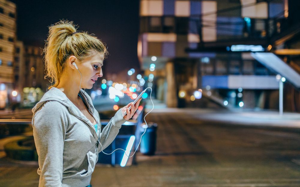 Sideview of blonde sportswoman checking exercise progress on mobile phone