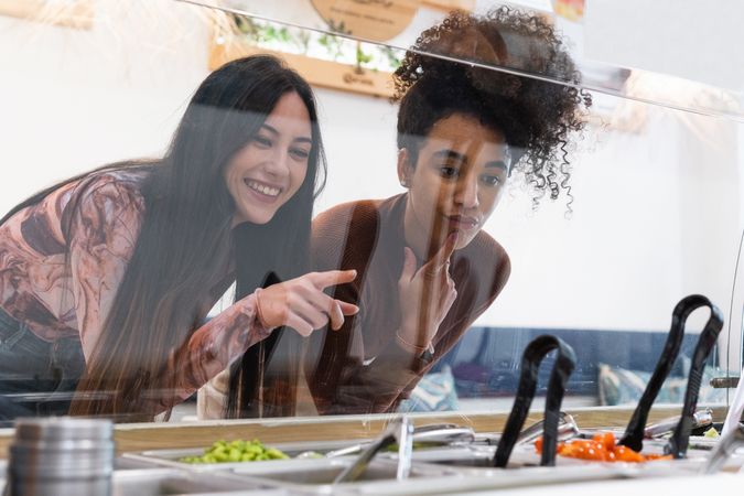 Multiethnic women choosing food in restaurant