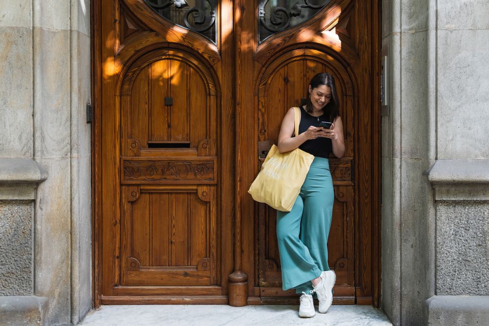 Content stylish woman using smartphone in street