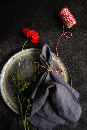 Rustic table setting with poppy flower and red string