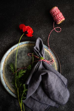 Rustic table setting with poppy flower and red string